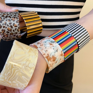 Detail of stacked acrylic cuff bracelets with leopard print and rainbow stripes