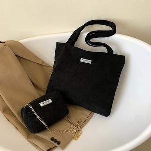 Detail of black corduroy tote bag set with matching chain pouch on light fabric background