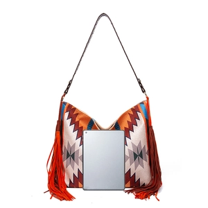 Detail of bohemian hand-woven hobo bag with fringe and tablet for size comparison