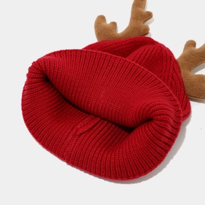 Detail of red knit Christmas beanie featuring brown plush reindeer antlers and thick ribbed texture
