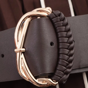 Close-up of dark brown leather belt with gold metal buckle and woven texture detail