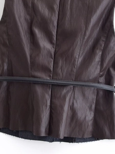 Détail de la texture en similicuir marron foncé avec une fine ceinture noire élégante