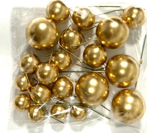Close-up of assorted gold ball cake toppers with green stems in clear plastic packaging