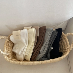 Detail view of multi-color cotton knit socks with ruffled edges in a woven basket