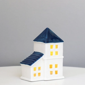 Ceramic LED house night light with white walls and blue roof emitting warm yellow glow