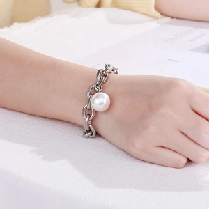 Minimalist silver chain bracelet featuring a large round pearl on a female wrist