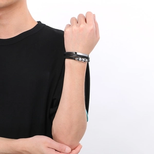 Close-up of multilayer braided leather bracelet with silver skull charms on male wrist