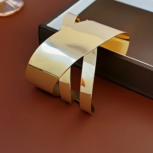 Macro shot of polished gold irregular cross cuff bracelet on a luxury jewelry box