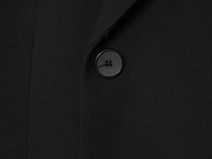 Gros plan détaillé d'un bouton en résine noir mat sur une veste blazer noire cintrée