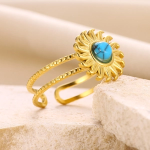 Macro shot of gold sunflower ring featuring a turquoise center on natural stones