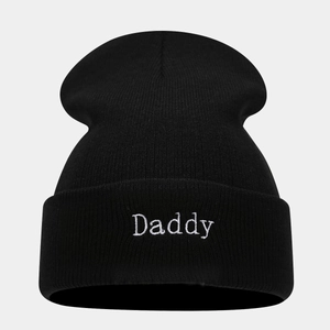 Close-up of white Daddy embroidery on black knitted beanie with cuffed design