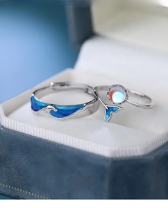 Detail of S925 silver couple rings with whale tail, moonstone, and blue enamel finish