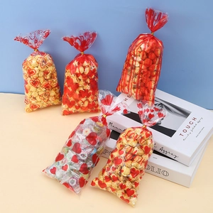 Transparent cellophane gift bags with red hearts and golden ties for cookies and candy