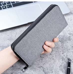 Close-up of a grey canvas long zip wallet for men being held in a business setting
