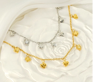 Close-up of golden and silver heart pendants with radial texture on white floral background