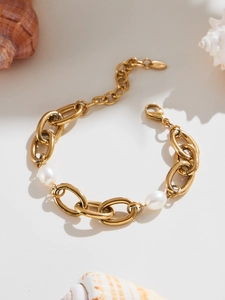 Detailed macro view of gold chain bracelet with pearl accents and lobster clasp closure