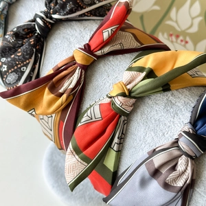 Detailed macro view of knotted satin headbands in vintage floral and geometric patterns