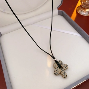 Detail of flower shaped stone pendant on black wax cord inside a jewelry box