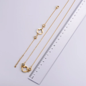 Detail of gold clover jewelry set with zircon inlay next to a ruler for size reference