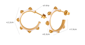 Detail von C-förmigen goldfarbenen Ohrringen mit weißem Emaille und Goldperlen