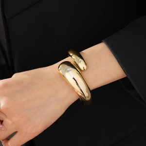 Polished chunky gold cuff bracelet with textured finish shown on a black blazer sleeve