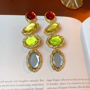 Vintage gold-tone drop earrings with colorful oval crystals on classic book background