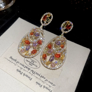 Macro detail of vintage hollow oval drop earrings featuring colorful gemstones and micro-diamonds