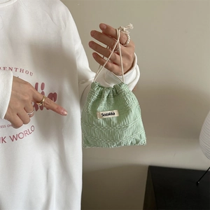 Detail of light green drawstring pouch featuring waffle texture and woven label