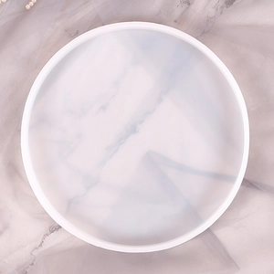 Flat lay of a round white marble pattern resin tray with raised edges on grey tulle