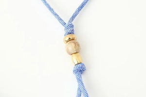 Macro shot of blue braided strap with gold metal accents and marbled beads detail