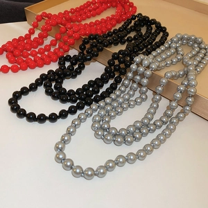 Detail of elegant red, black and grey faux pearl long necklaces on a gold tray