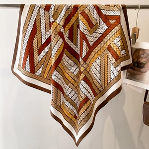 Close-up of square silk scarf showing geometric weave pattern in brown and gold