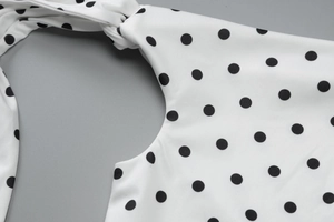 Detailed view of the elegant polka dot print dress showing neckline and tie shoulder detail