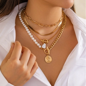 Detail of layered gold necklaces with baroque pearl and Elizabeth II coin pendants