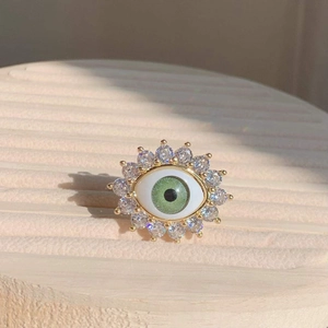 Detail of evil eye ring with green resin eye, white enamel and sparkling zircon stones