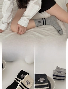 Close-up of ribbed cotton crew socks with athletic stripes and letter embroidery