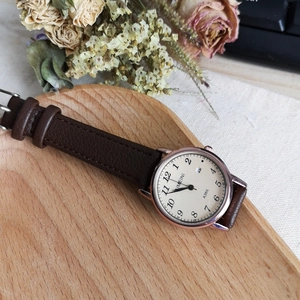 Close-up of IMEINI quartz watch with rose gold case and date display on a wooden tray