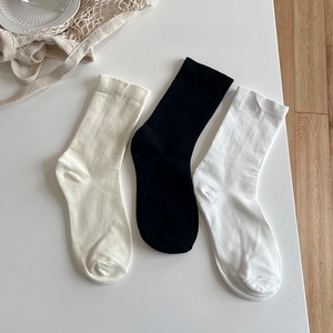 Flachbild von Baumwollsocken in Creme, Schwarz und Weiß auf einem sauberen Tisch