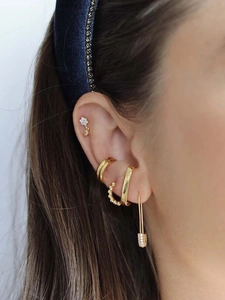 Detailed view of gold earring stack with white zircon butterfly and safety pin charm