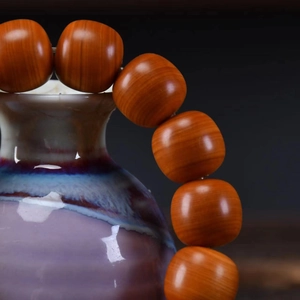 Close-up of Taihang Cypress wood prayer beads with natural grain on a ceramic vase