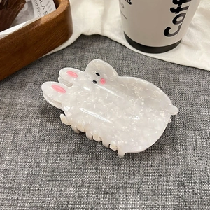 Detailed view of a white rabbit-shaped hair claw clip with pearlescent resin finish