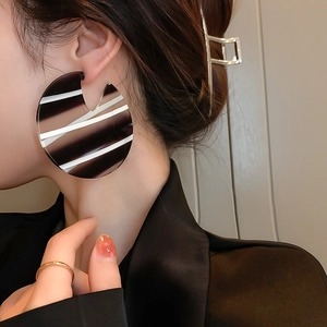 Close-up of oversized acrylic hoop earrings featuring bold black and white stripes