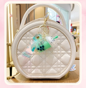 Detailed macro view of a quilted leather bag with a cat milk tea liquid pendant keychain