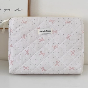 Pink polka dot quilted cosmetic bag with ribbon bow and embroidered fabric label