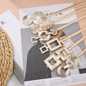 Ceintures dorées élastiques en métal avec boucles géométriques sur fond lifestyle chic