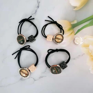 Close-up of hair ties featuring gold square charms with iconic red and green stripe accents