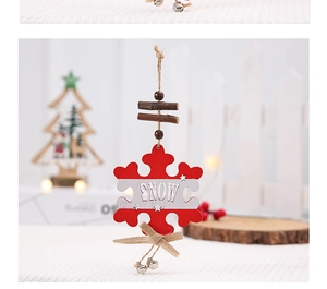Detail of red wooden snowflake ornament with SNOW banner and small bells on jute rope