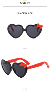 Close-up of heart-shaped kids sunglasses with red bow detail in black and red finish