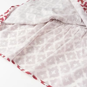 Détail d'un tissu léger avec des bords rouge-blanc et des motifs géométriques gris