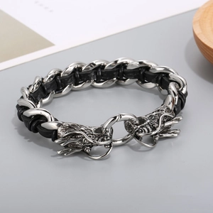 Detalle de cierres de cabeza de dragón en pulsera punk de cuero trenzado y acero hombre